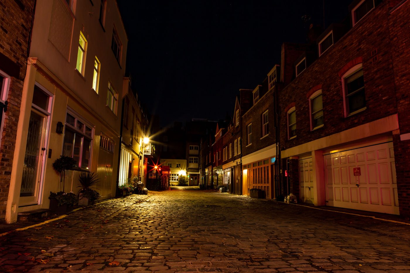 Cobbled London mews at night lit by warm lamps