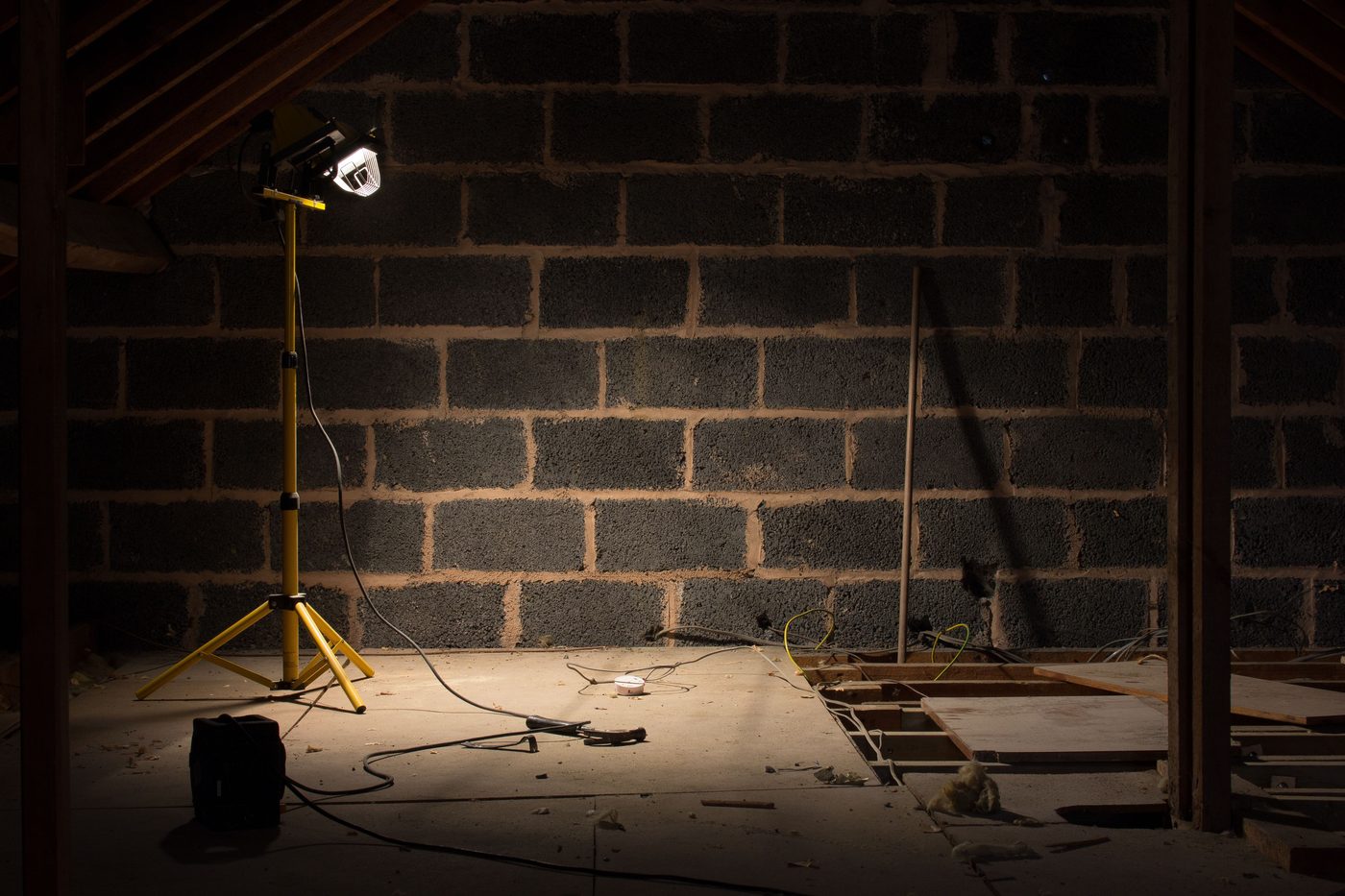 Loft space lit by a single work lamp during a repair
