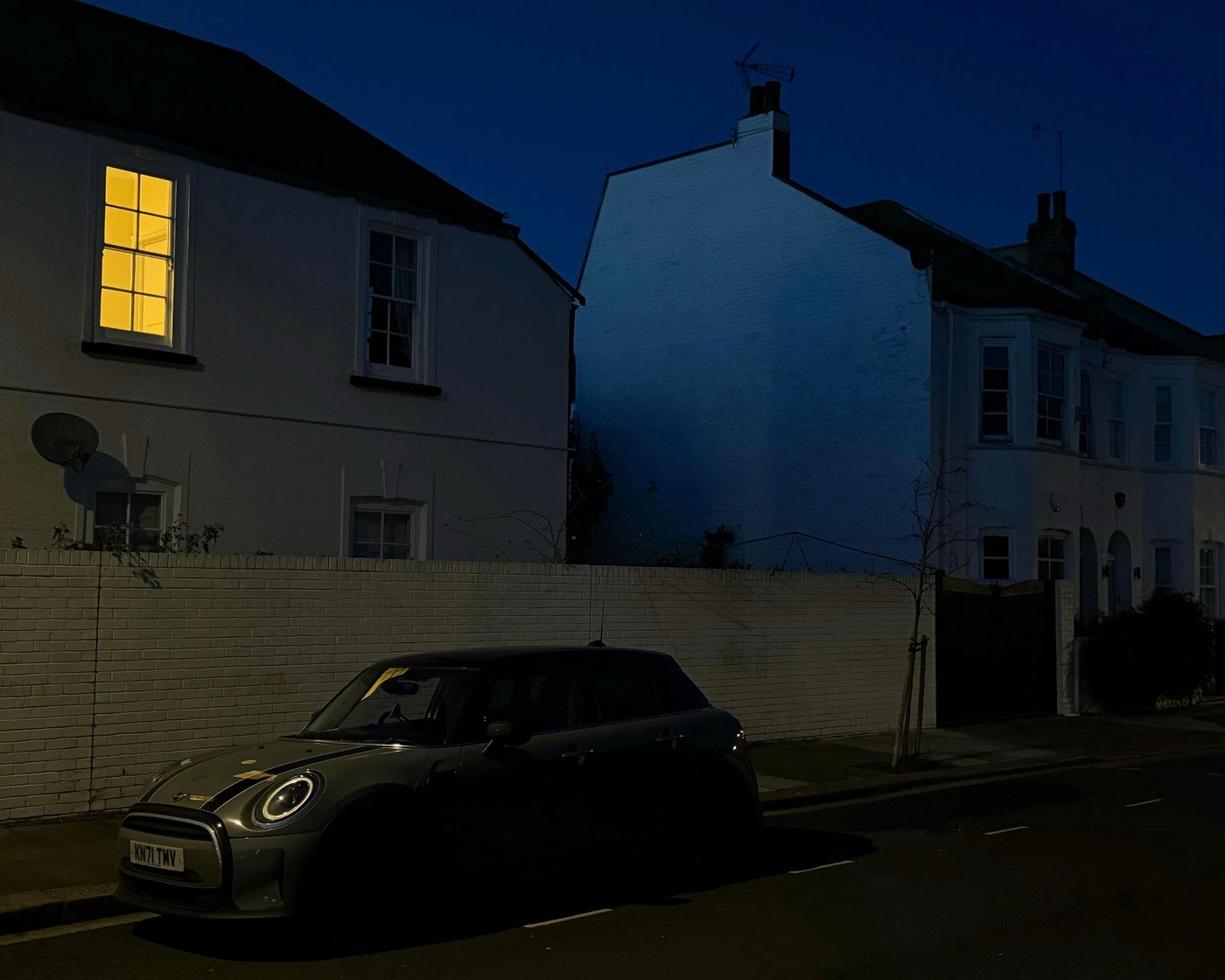 Quiet London residential street at night with one lit window